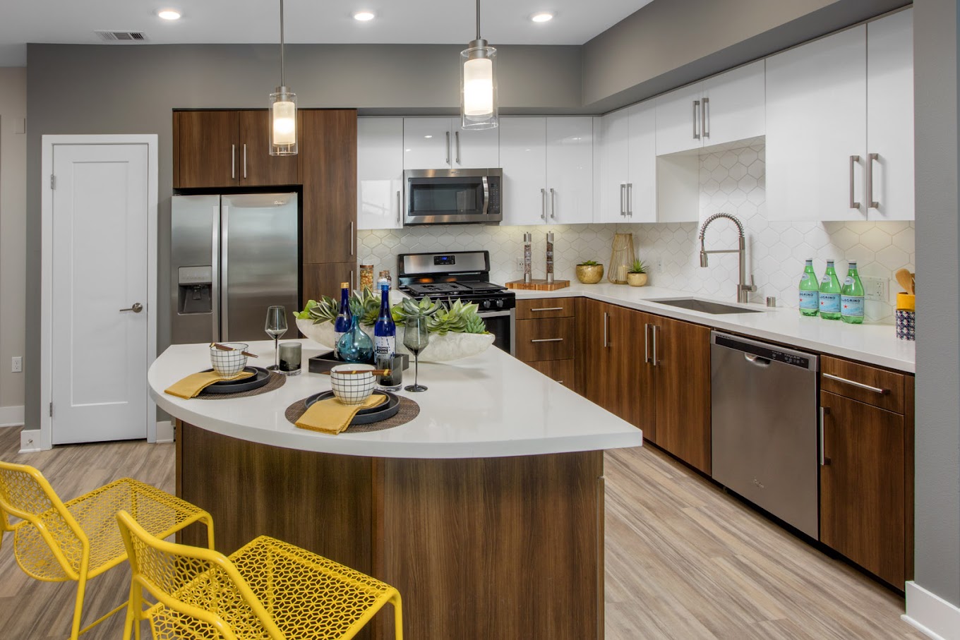 Stainless Steel Appliances, Contemporary wood-look plank flooring, glossy white cabinetry, quartz countertops, full tile backsplash, pendant lighting in kitchen islands