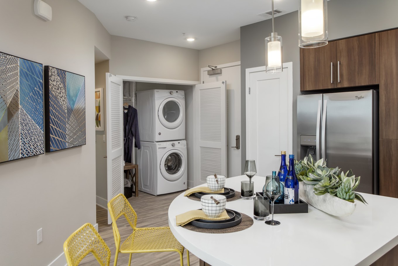 Stainless Steel Appliances, Contemporary wood-look plank flooring, glossy white cabinetry, quartz countertops, full tile backsplash, pendant lighting in kitchen islands
